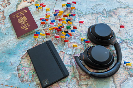 Poland, Gdansk - 19 April 2020: Polish passport, notebook and headphones on a colored world map with embedded flags. Travel or tourism concept.のeditorial素材