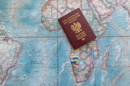 Poland, Gdansk - 19 April 2020: Polish passport on a colored world map with embedded flags. Travel or tourism concept.のeditorial素材
