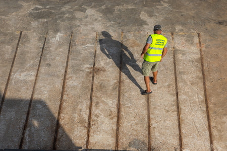 Folegandros, Greece- 26 September 2020: View of the harbor of Folegandros Island. A man, a port worker in a yellow reflective T-shirt.のeditorial素材