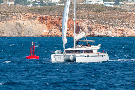 Paros, Greece - 26 September 2020: Catamaran departing from the port. Hills with White traditional buildings in the background.のeditorial素材