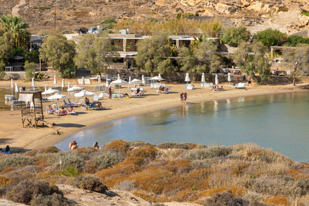 Monasteri Beach, Paralia, Paros Island, Greece - 27 September 2020: One of the most popular beach on Paros. People sunbathing on the sun loungers under straw umbrellas.のeditorial素材