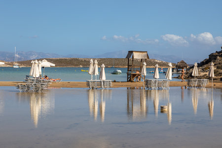 Monasteri Beach, Paralia, Paros Island, Greece - 27 September 2020: One of the most popular beach on Paros. People sunbathing on the sun loungers under white umbrellas.のeditorial素材