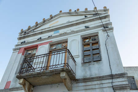 View of the facade of a ruined building in Lefkes. Windows boarded up, Lefkes, Paros island, Greece.の写真素材