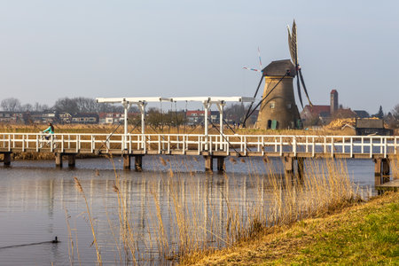 Kinderijk, Netherlands - 11 March 2016: View of the Famous windmills, Lek Canal and white bridge. Vicinity of the museum UNESCO World Heritage Kinderdijk.のeditorial素材