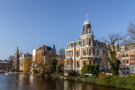 Amsterdam, Netherlands - March 12, 2016: Netherlands houses along river Amstel. Landmark old european city, spring landscape.のeditorial素材