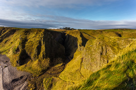 View of the path to the Dunnottar Castle between green hills. Beautiful sunny morning. Stonehaven, Aberdeenshire, Scotland, United Kingdom.のeditorial素材