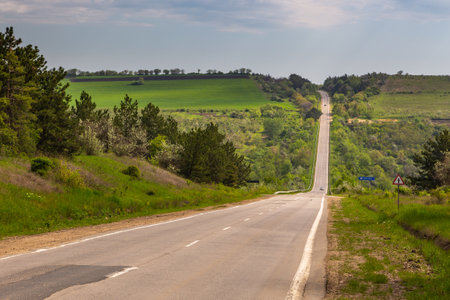 Republic of Moldova - 01 May 2016: A country road among meadows and fields. Spring season rural landscape.のeditorial素材