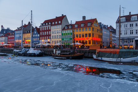 Copenhagen, Denmark - 06 March 2018: Nyhavn in the evening. A 17th-century waterfront, canal and entertainment district with brightly colored townhouses, bars, pubs, restaurants and historical ships.のeditorial素材