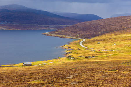 View of the Leitisvatn Lake above the Ocean. Walking area, peat field, and Traelanipan Trail. Cloudy day on the Vagar island. Faroe Islands.の写真素材