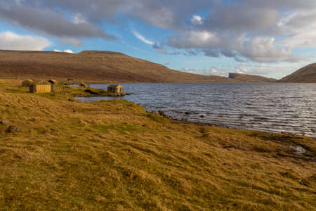 Old stone buildings for storing boats on Lake Leitisvatn on the island of Vagar. Beautiful sunset. Faroe Islands.の写真素材