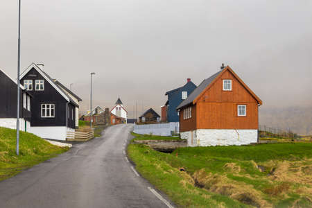 Small village Hellur situated on the slope of the mountain on Eysturoy island. Church in the background. Faroe Islands, Denmark.の写真素材