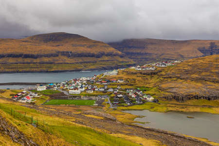 Small village Eidi situated on the slope of the mountain on Eysturoy island. Football playground. Eidi, Faroe Islands, Denmark.の写真素材