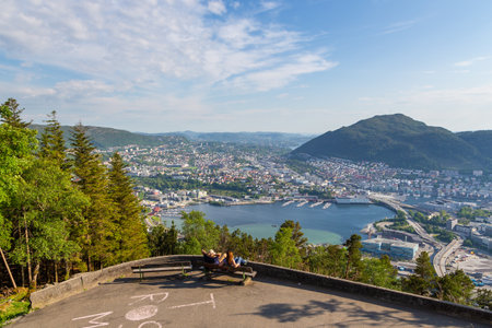 Bergen, Norway - 28 May 2018: People sitting on a bench on Floyen Hill. View of the city and the fjord in the background.のeditorial素材