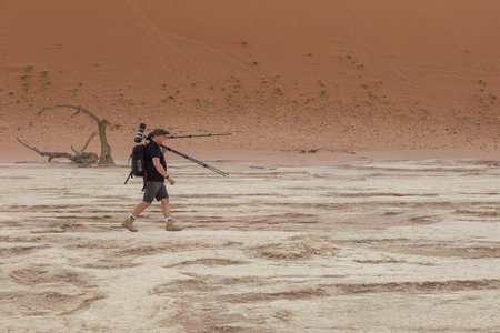 Deadvlei, Namibia - 30 September 2018: Man taking photo in Deadvlei, white clay pan located inside the Namib-Naukluft Park in Namibia. Dead acacia trees. Colorful dunes in the background.のeditorial素材