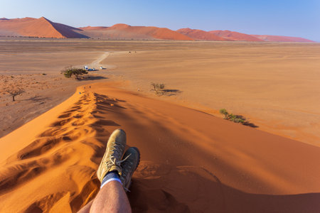 Sesriem, Sossusvlei, Namibia - 30 September 2018: A tourist in the shoes of the renowned Meindl brand. Mountain, climbing and trekking shoes. Famous dune 45.のeditorial素材