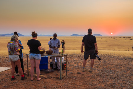 Solitaire, Namibia - 01 October 2018: Refreshments for safari. Tourists at the table. Sunset over the savannah in the background. Beautiful landscape.のeditorial素材