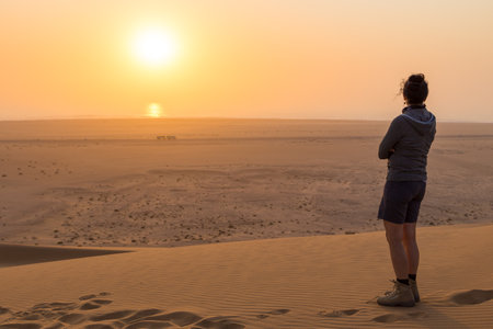 Swakopmund, Namibia - October 03, 2018: Girl in the dunes. Sunset over the northern part of the Namib Desert. Desert off the coast of the Atlantic Ocean, Walvis Bay.のeditorial素材