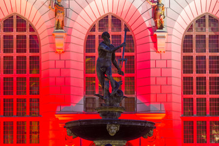 Gdansk, Poland - 10 November 2018: Beautiful illumination of the The Artus Court at Dluga Street in old historic town. Neptune statue in front off.のeditorial素材