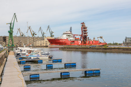 Gdansk, Imperial Shipyard, Poland - 01 May 2019: Ship moored at the quay of the shipyard. Cranes in...