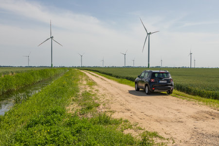 Stegna, Poland - 15 June 2019: Glade road in the middle of the fields. spring season. Windmills in...