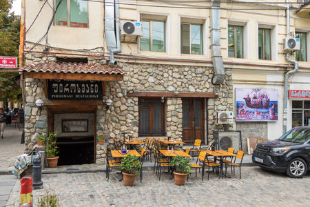 Georgia, Tbilisi - August 30, 2019: Tables in the garden of the restaurant. Stone facade traditional...