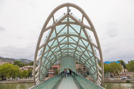 Tbilisi, Georgia - August 30, 2019: The Bridge of Peace, a bow-shaped pedestrian bridge, a steel and glass construction over the Kura River.のeditorial素材