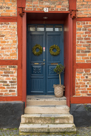 Close-up of a blue door with decorative wreaths in a traditional red brick and timber-framed house in Ystad, Sweden.の写真素材