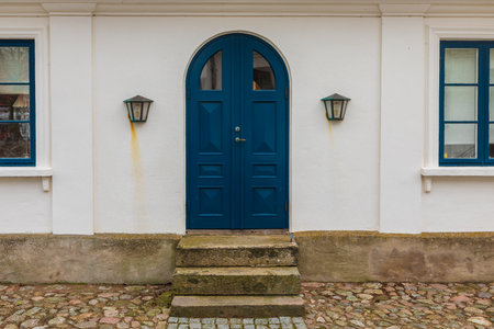 Blue arched front door and lanterns on a white wall with stone steps in Torekov, Sweden.の写真素材