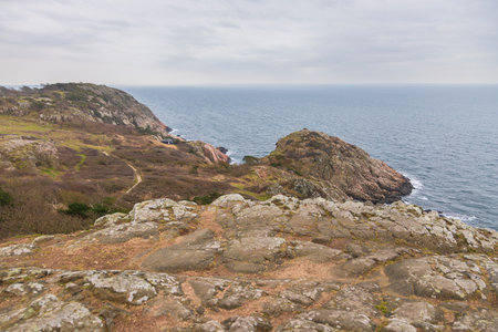 Dramatic rocky coastline with a small white lighthouse on the edge of the cliffs in Kullen, Sweden.の写真素材