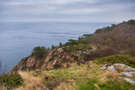 Dramatic rocky coastline with a small white lighthouse on the edge of the cliffs in Kullen, Sweden.の写真素材