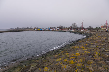 Colorful fishing huts and harbor structures line the rocky shore at the southernmost point of Sweden.の写真素材