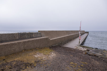 A long concrete pier and breakwater at the southernmost point of Sweden in overcast weather.の写真素材
