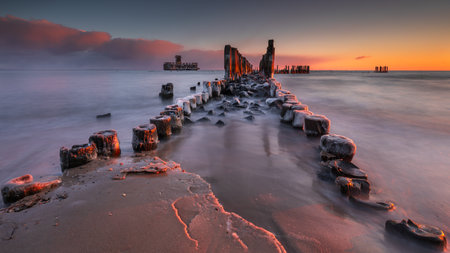 Frozen breakwater and sea waves at sunrise in Babie Doly, Gdynia, Poland â visible torpedo station ruins.の写真素材