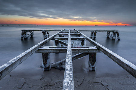 Old wooden pier covered in ice at dawn on the Baltic Sea in Sopot, Poland. Peaceful winter seascape.の写真素材