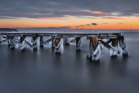 Old wooden pier covered in ice at dawn on the Baltic Sea in Sopot, Poland. Peaceful winter seascape.の写真素材