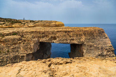 Natural limestone rock window overlooking the Mediterranean Sea on the rugged coast of Gozo Malta.の写真素材