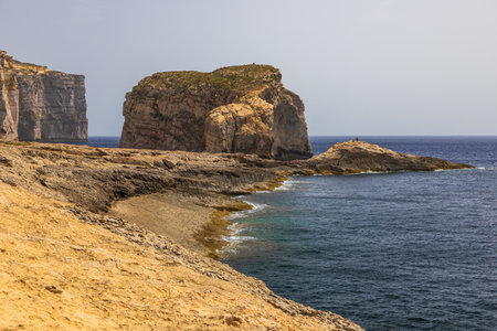 Steep rocky cliffs and rugged shoreline along the Mediterranean coast of Gozo Malta under clear sky.の写真素材