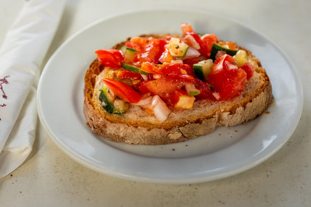 Close-up of bruschetta with fresh tomato, cucumber, and onion served on a slice of bread in...