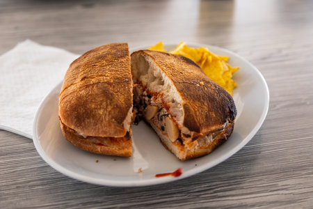Close up of a toasted sandwich with filling and tortilla chips on a plate in Il Brolli, Malta.の写真素材
