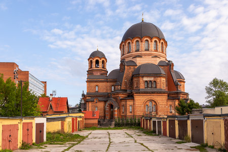 Orthodox cathedral with dark domes and red brick walls surrounded by old garages and urban buildings...
