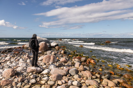 Lahemaa, Estonia â September 01, 2021: Person standing on a rocky Baltic Sea shore with waves hitting the coastline in Lahemaa National Park.のeditorial素材