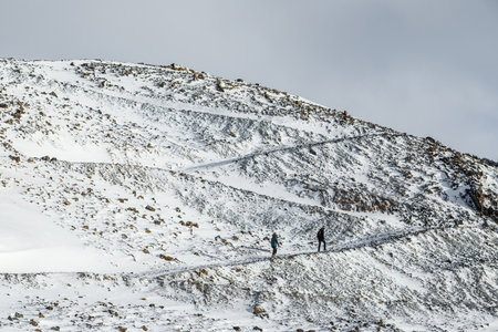 Grindavik, Iceland â€“ February 06, 2022: Group of hikers walking along a snowy trail in a...