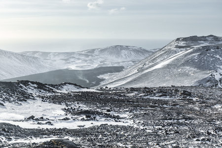 Wide view of a snow covered volcanic landscape with lava rocks and mountains on the Reykjanes Peninsula near Grindavik, Iceland, during winter.の写真素材