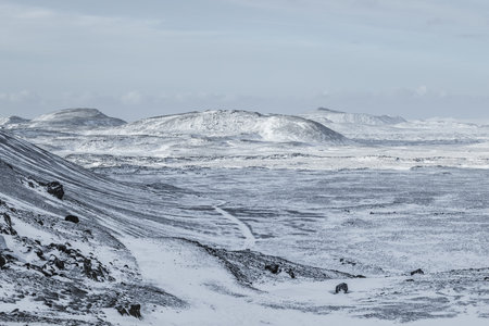 Wide view of a snow covered volcanic landscape with lava rocks and mountains on the Reykjanes Peninsula near Grindavik, Iceland, during winter.の写真素材