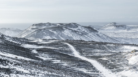 Wide view of a snow covered volcanic landscape with lava rocks and mountains on the Reykjanes Peninsula near Grindavik, Iceland, during winter.の写真素材