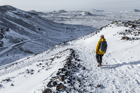 Grindavik, Reykjanes Peninsula, Iceland â€“ February 6, 2022. Lone hiker walking along snowy...