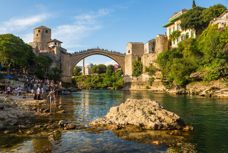 Mostar, Bosnia and Herzegovina â August 16, 2022: People gathering along the Neretva River beneath the historic Stari Most bridge, a UNESCO World Heritage Site in the old town of Mostar.のeditorial素材
