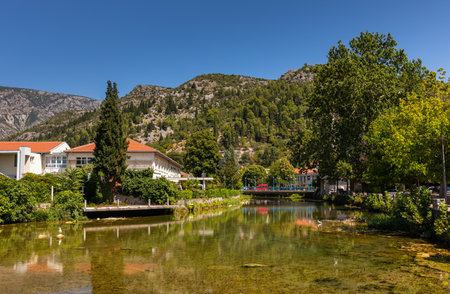 Stolac, Bosnia and Herzegovina - 2022 August 17: Bregava river passing through Stolac town with green mountains under a clear skyのeditorial素材