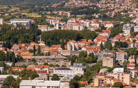 Trebinje, Bosnia and Hercegovina - August 21, 2022: Trebinje city buildings and green trees under clear blue sky.のeditorial素材