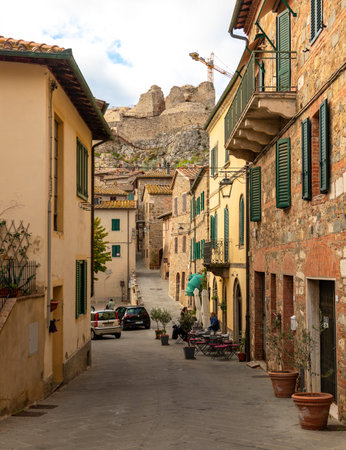 Castiglione dOrcia, Italy - November 07, 2022: Old stone buildings lining a narrow street with Rocca Aldobrandesca fortress ruins in the background.のeditorial素材